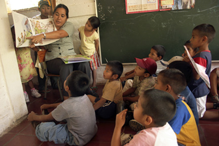 Woman reading a book with young children in Estancia, El Salvador 